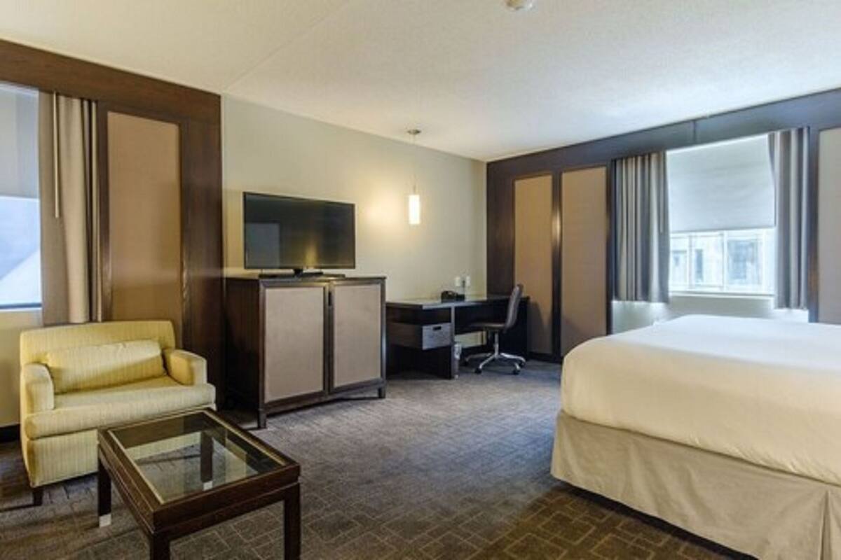 A hotel room with a bed, a desk, a television, and a sofa.