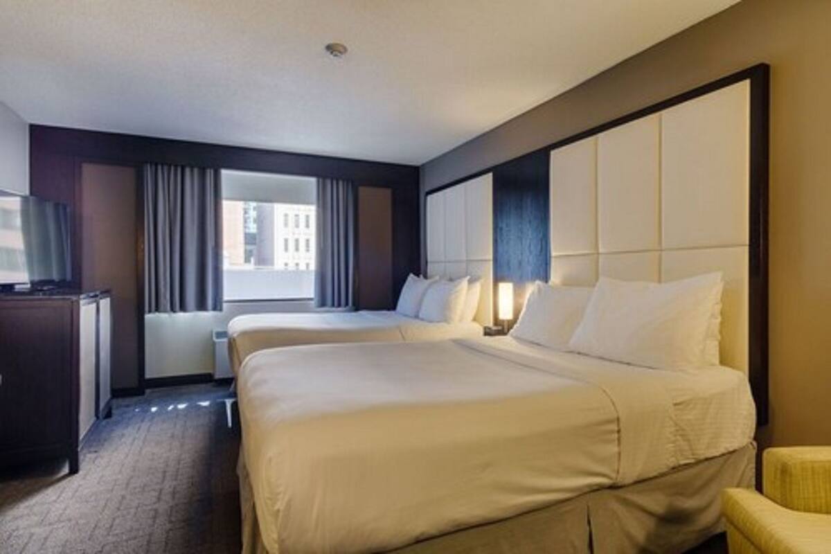 A hotel room with two beds, a desk, and a chair.