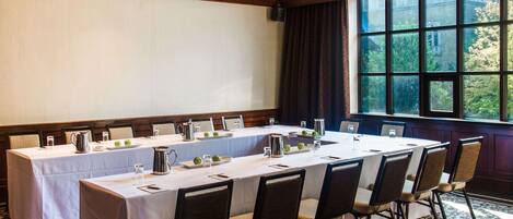A conference room with a long table, chairs, and a projector screen.