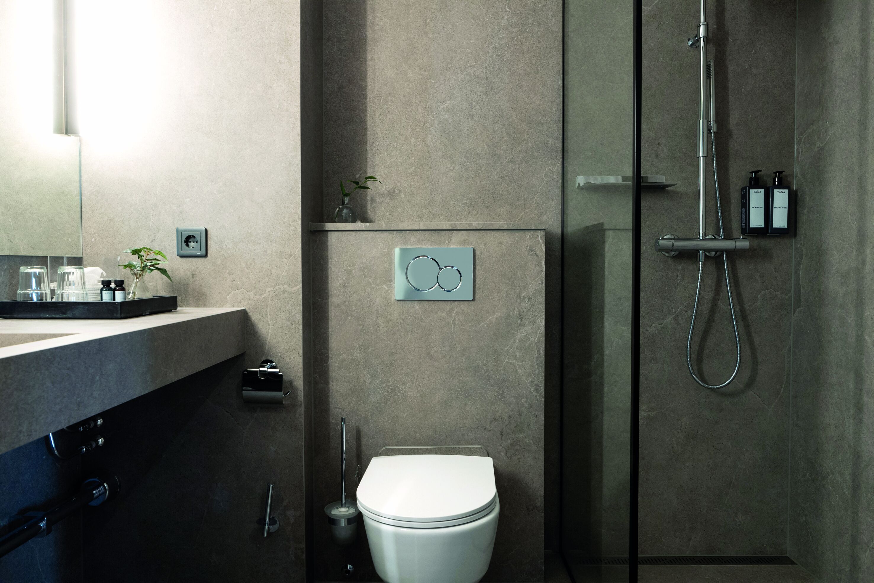A modern bathroom with a toilet, a shower, and a sink.