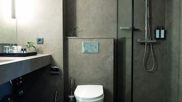 A modern bathroom with a toilet, a shower, and a sink.