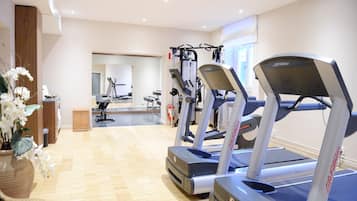 Une salle de sport équipée de tapis de course, d’appareils d’exercice et dotée d’un plancher en bois.