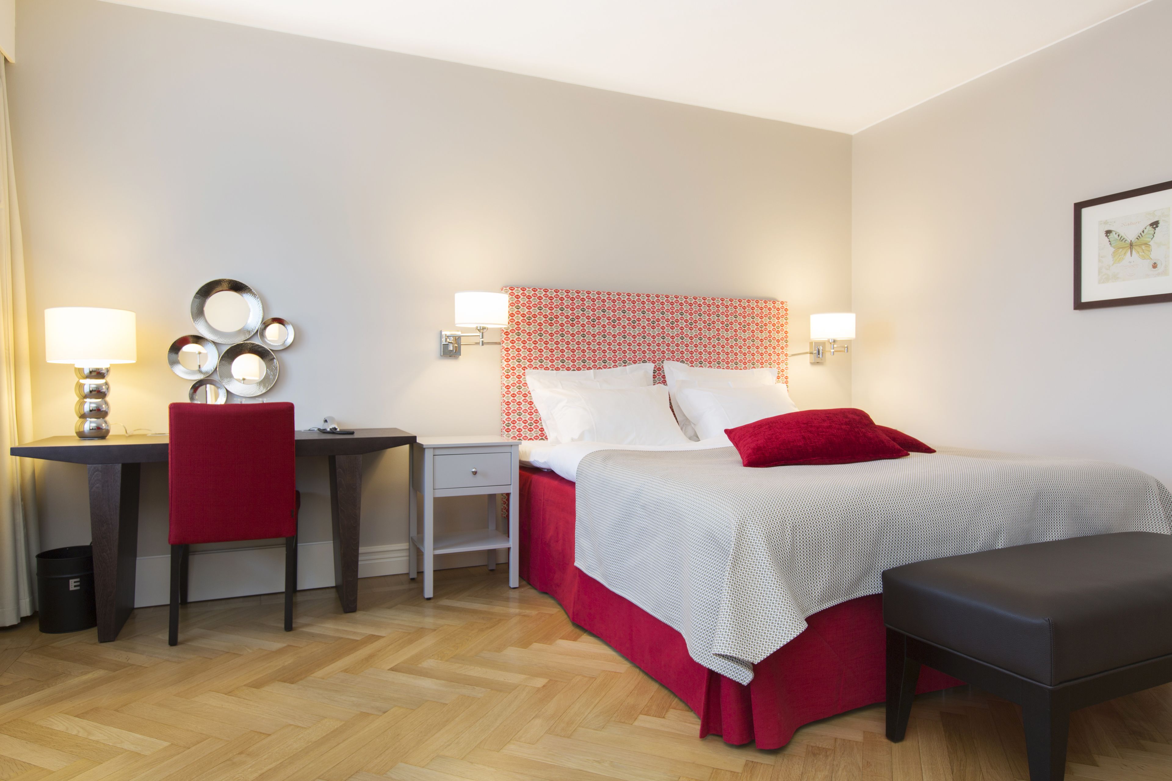 Une chambre d’hôtel comprenant un lit, un bureau, une chaise, une table de chevet et un banc.