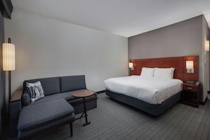 Ein Hotelzimmer mit einem Bett, einer Couch, einem kleinen Tisch und einem Nachttisch.