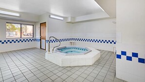 A clean, spacious bathroom with a freestanding bathtub, tiled floor, and a window providing natural light.