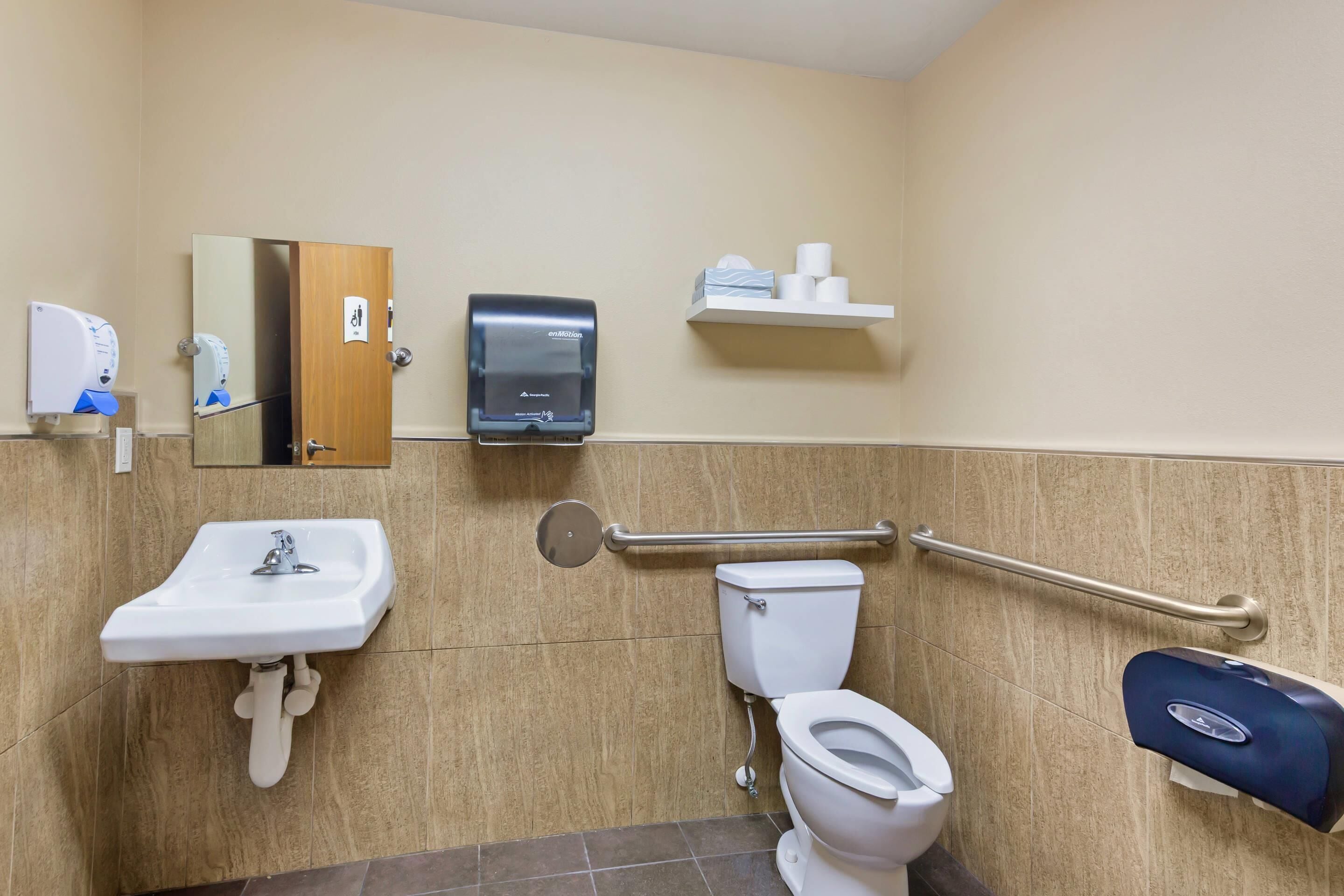 A bathroom with a sink, toilet, and hand dryer.