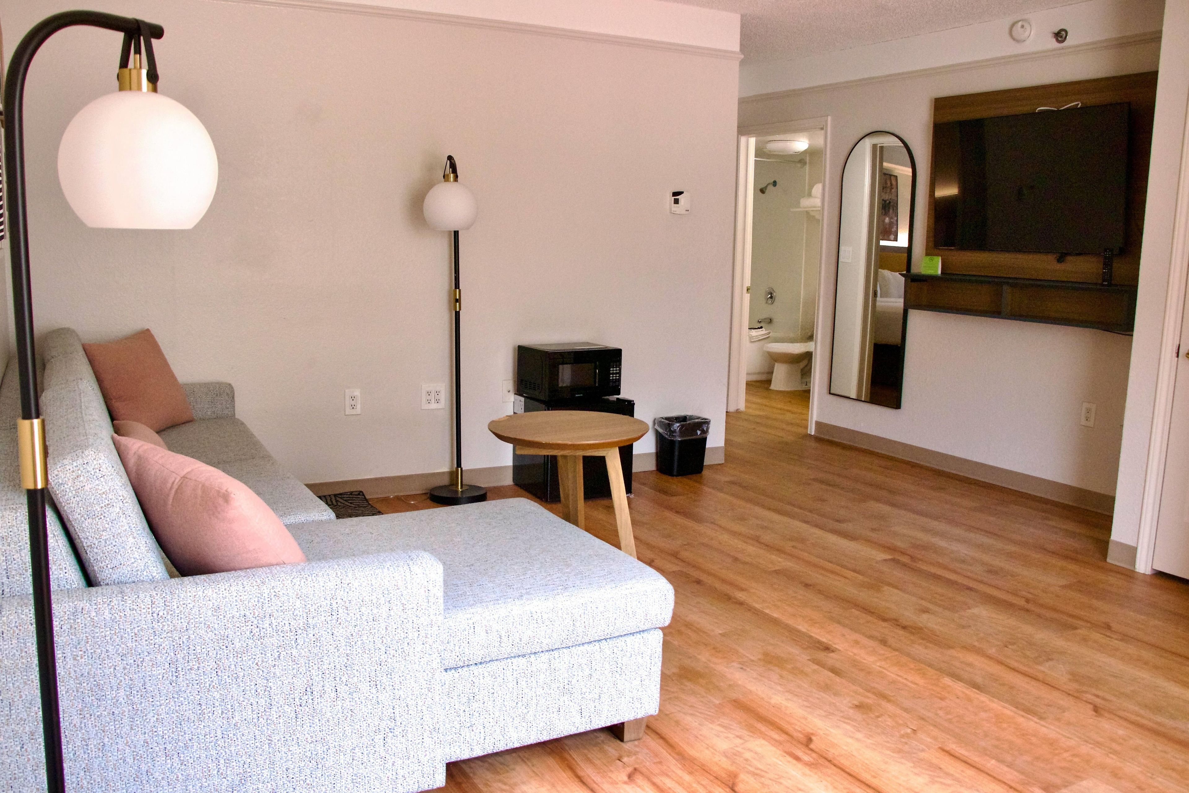 A living room with a sofa, a floor lamp, a small table, and a microwave.