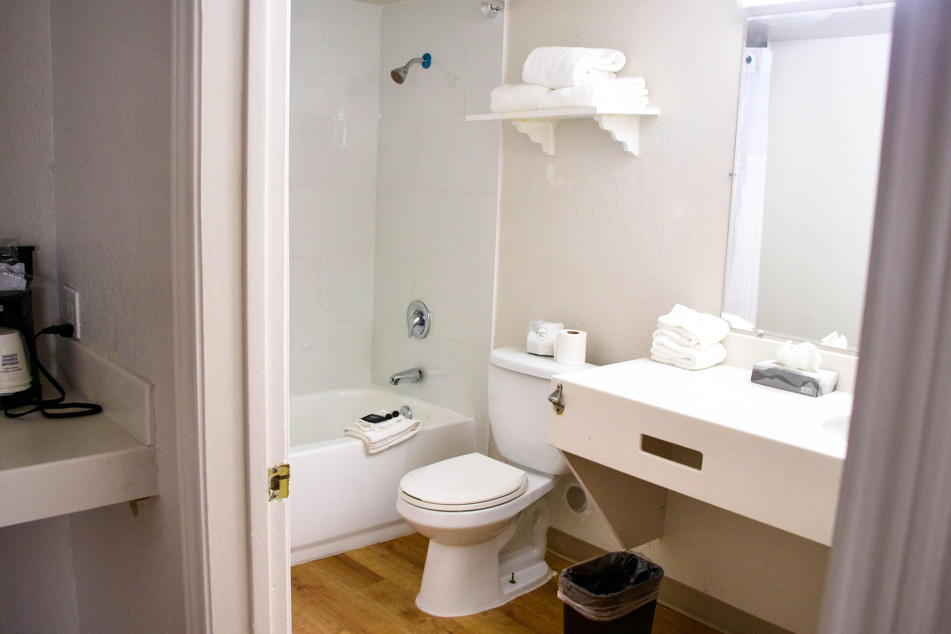 A bathroom with a toilet, a bathtub, a shower, and a sink area with a mirror.