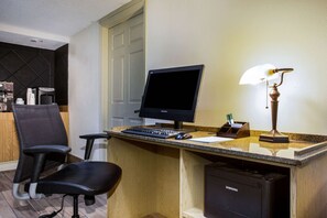 A hotel room with a desk, a computer, a chair, a lamp, and a Samsung dishwasher. - La Quinta Inn by Wyndham Austin Capitol / Downtown (Austin)