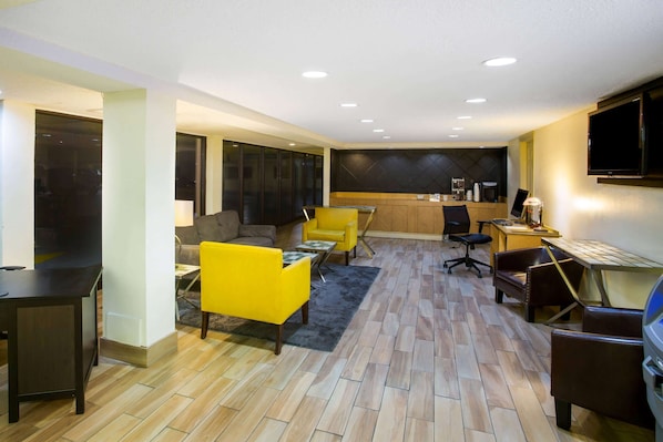 Un salon moderne avec un canapé, un fauteuil jaune et un coin repas comprenant une table et des chaises.
