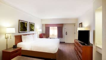 A hotel room with a large bed, a television, a desk, and a chair.