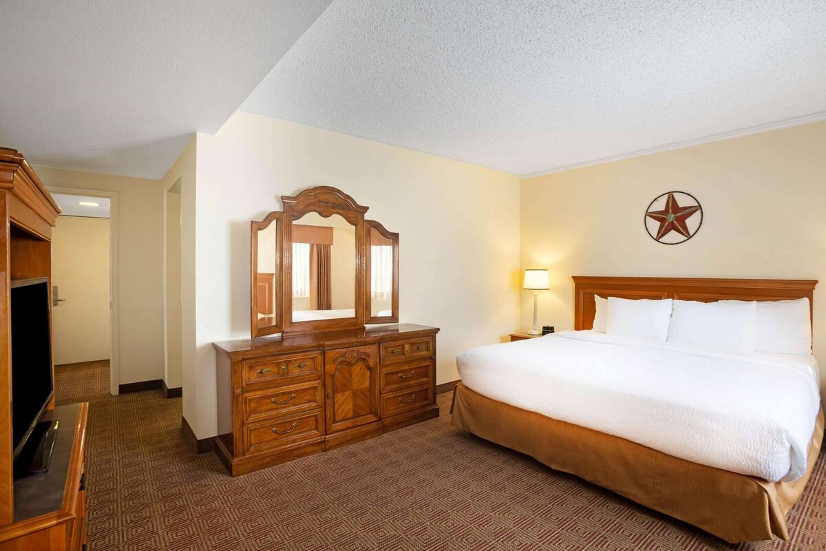 Una habitación de hotel con una cama grande, un aparador de madera y un adorno con forma de estrella en la pared.
