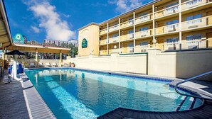 Een hotel met een zwembad, een overdekt gedeelte met parasols, en een gebouw met balkons.