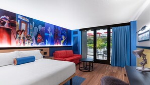 A hotel room with a bed, a red sofa, a small round table, and a balcony with blue curtains. - Pixar Place Hotel (Anaheim)
