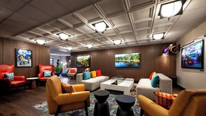 A modern lounge area with leather sofas, a coffee table, and a flat-screen TV mounted on the wall. - Pixar Place Hotel (Anaheim)