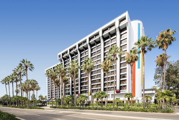 A multi-story hotel with a modern design, featuring balconies and a prominent vertical stripe on the facade.
