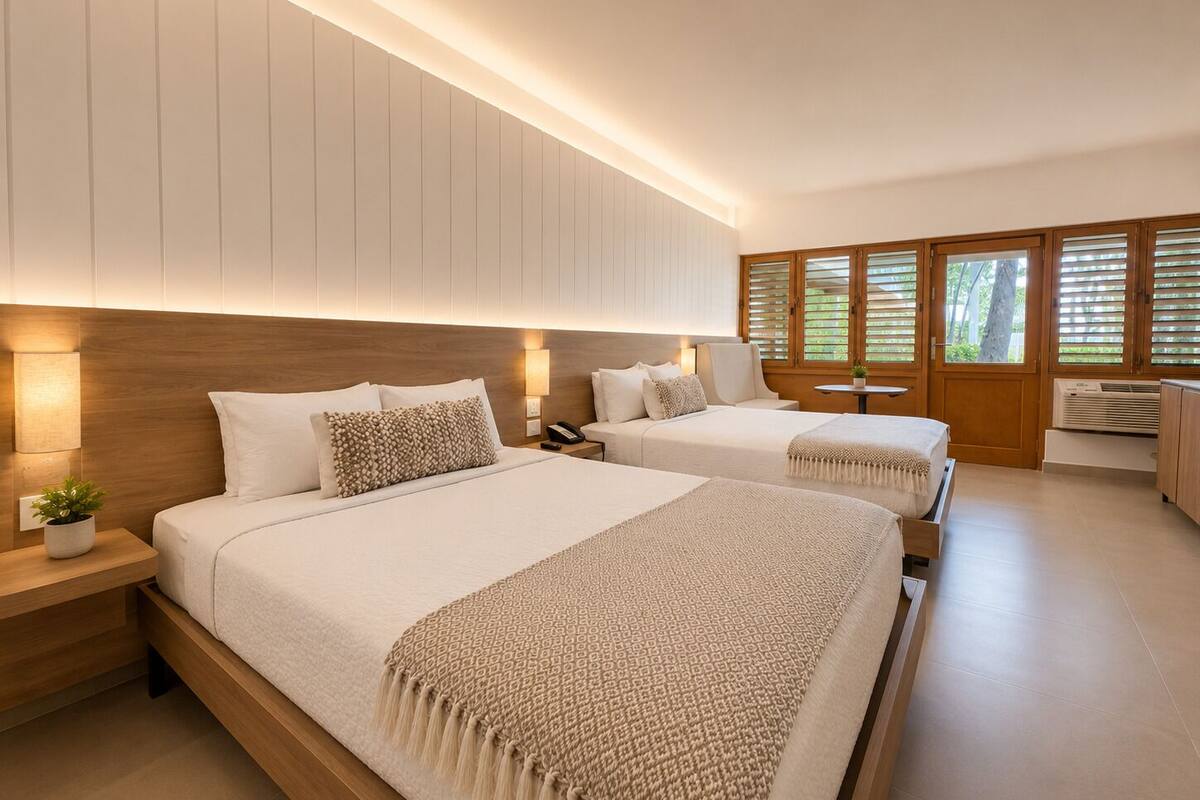 Ein modernes Hotelzimmer mit zwei Betten, einem Holz-Kopfteil, Nachttischlampen, einem kleinen Tisch mit Pflanze und einem Fenster mit Jalousien.
