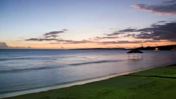 A beach with a small hut and calm water.