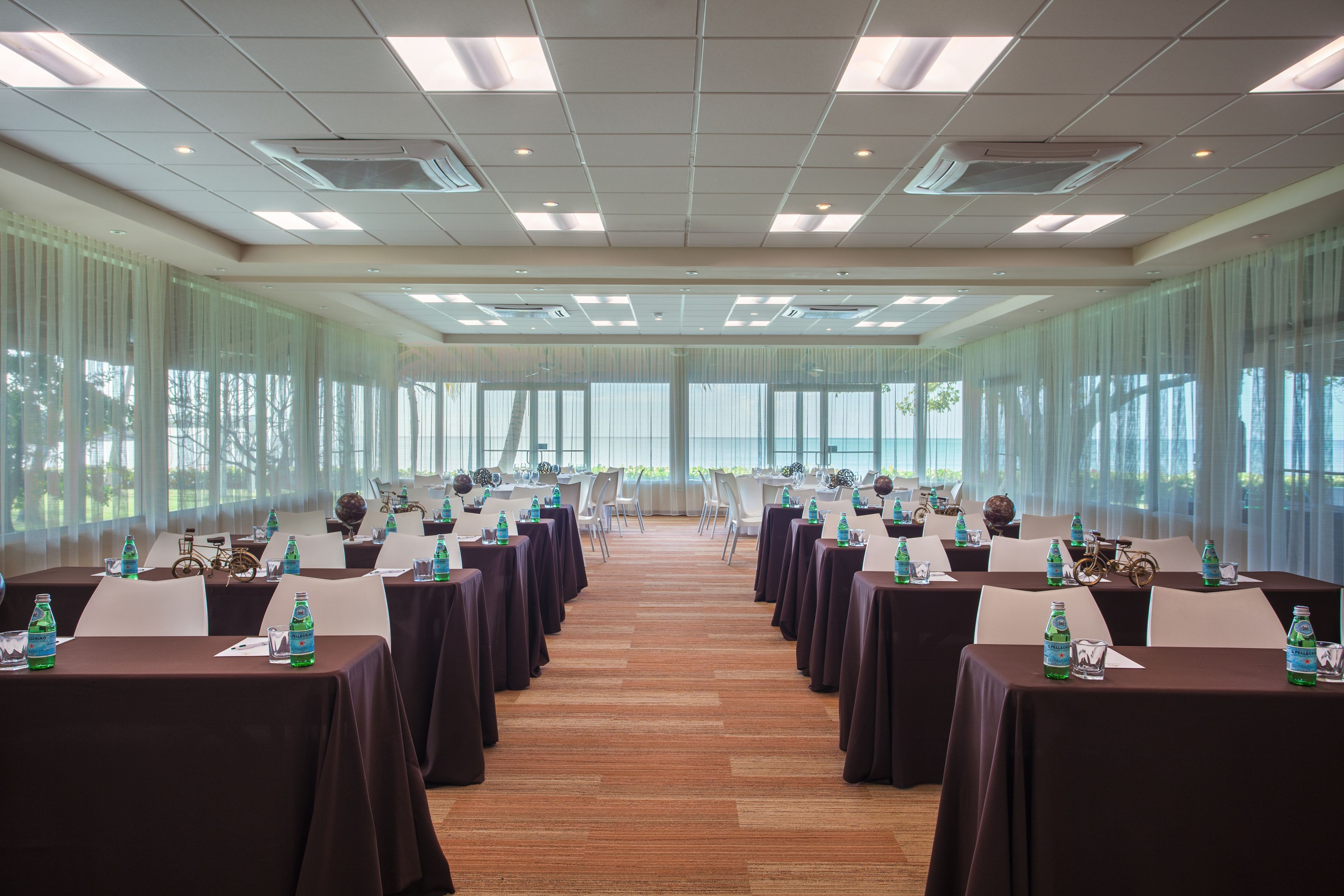 A conference room with tables set for a meeting, large windows, and a view of the outdoors.
