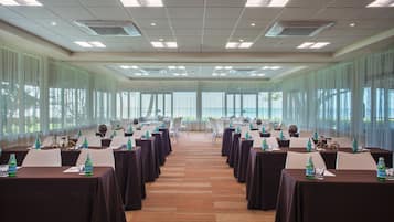 A conference room with tables set for a meeting, large windows, and a view of the outdoors.