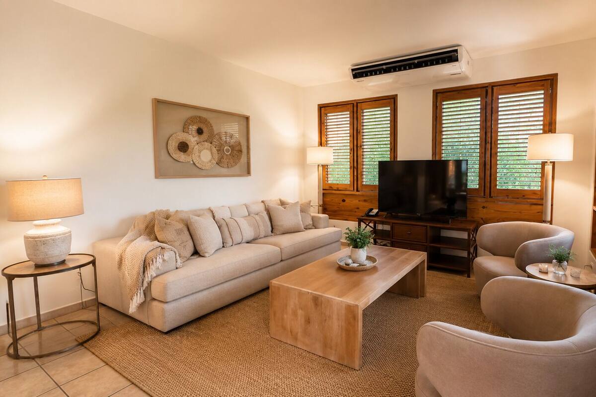 Ein Wohnzimmer mit einer Couch, einem Couchtisch, einem Fernseher und zwei Sesseln.