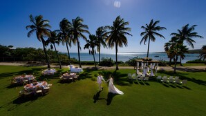 A wedding ceremony on a grassy lawn with tables and chairs, palm trees, and a gazebo. - Copamarina Beach Resort & Spa (Guanica)