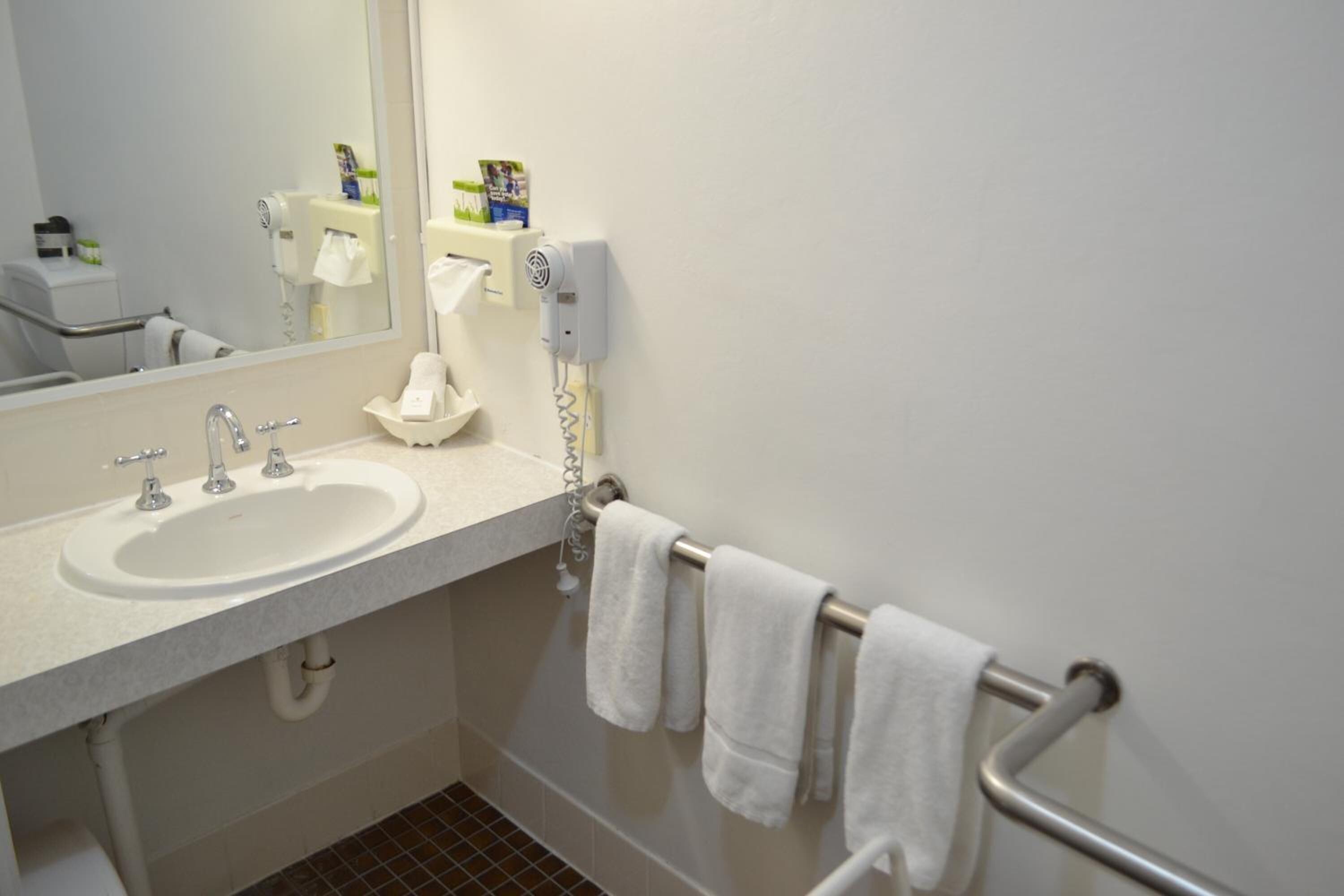 A bathroom with a sink, mirror, towel rack, and a hand dryer.