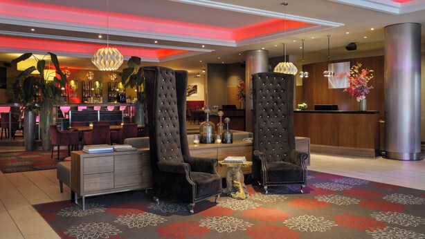 Eine moderne Hotelhalle mit Empfangstresen, einer Sitzecke und einer Bar.