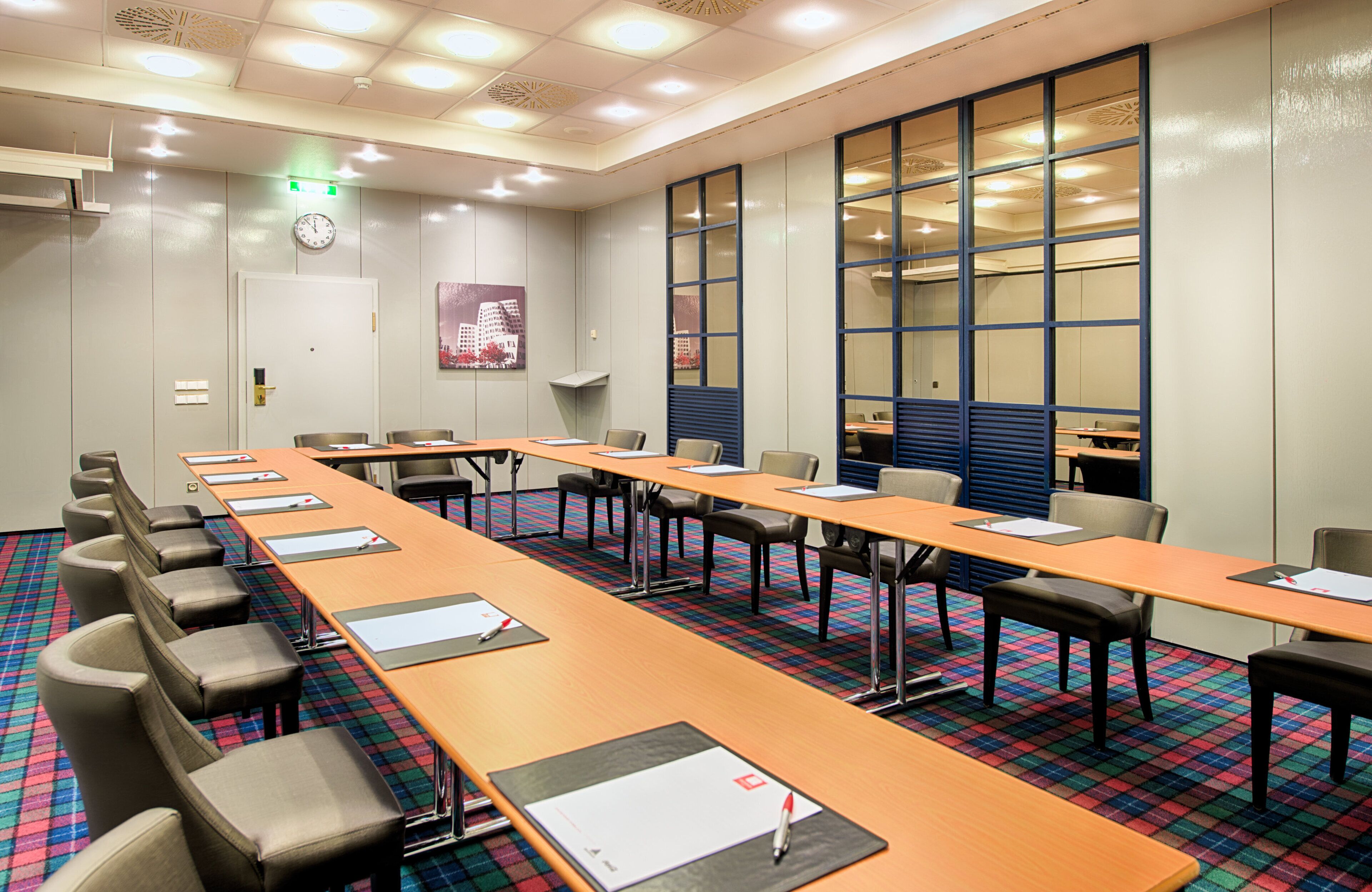 A conference room with a long table, chairs, and a clock on the wall.