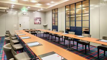 A conference room with a long table, chairs, and a clock on the wall.