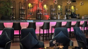 Eine Bar mit verschiedenen Sitzgelegenheiten, einer Auswahl an Flaschen in Regalen und dekorativer Beleuchtung.