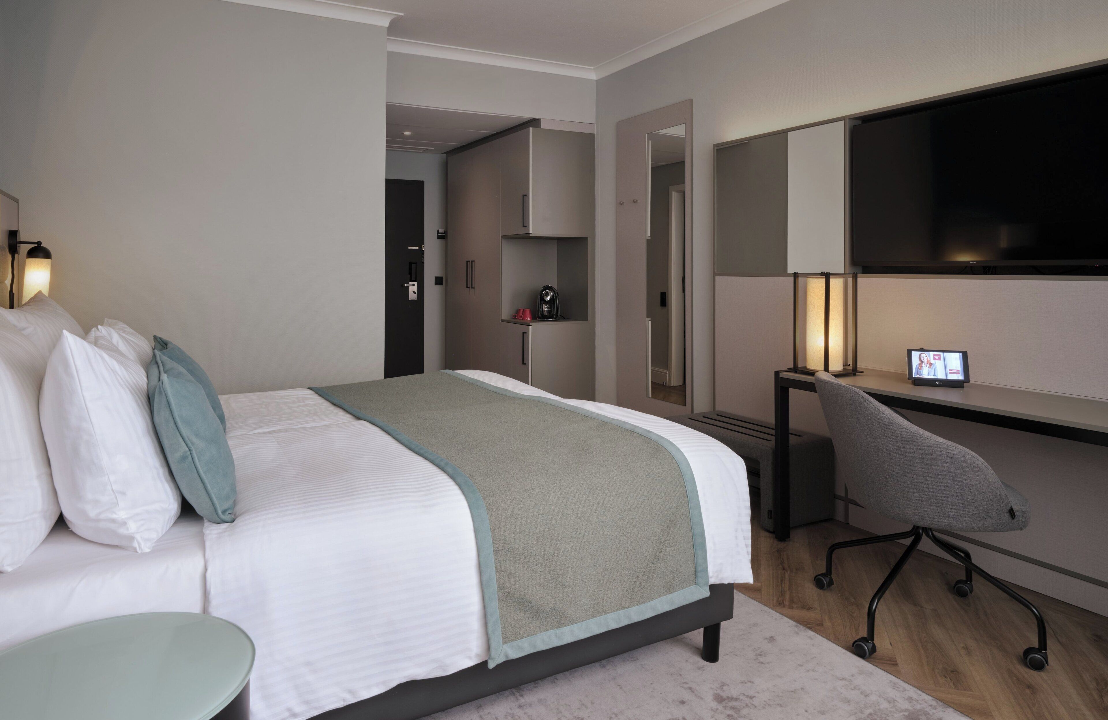 Una habitación de hotel moderna con una cama grande, un escritorio y un televisor.