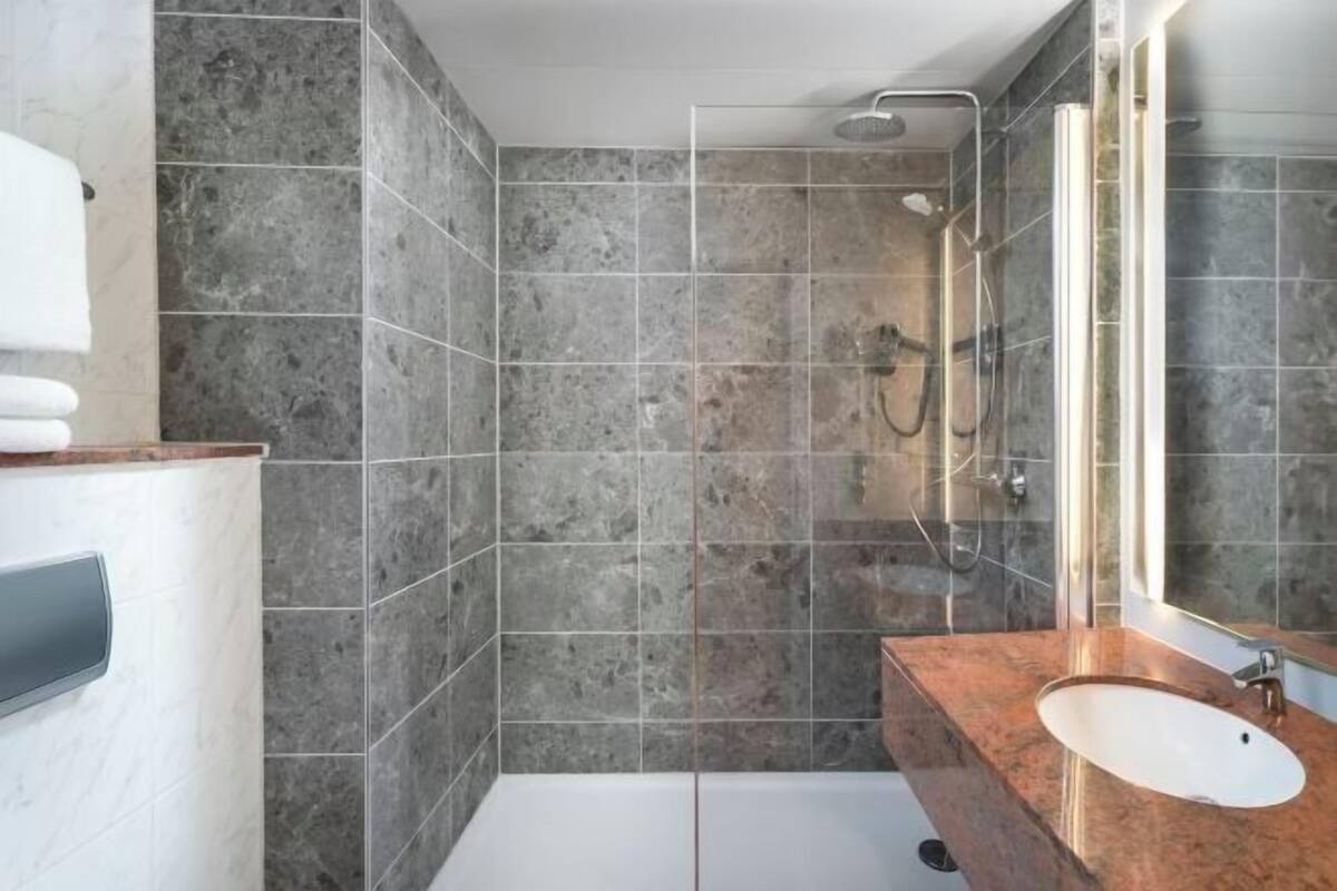 Un baño moderno con ducha, lavamanos y un espejo grande.