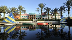 A marina with boats docked, palm trees, and colorful buildings in the background. - Disney's Caribbean Beach Resort (Lake Buena Vista)