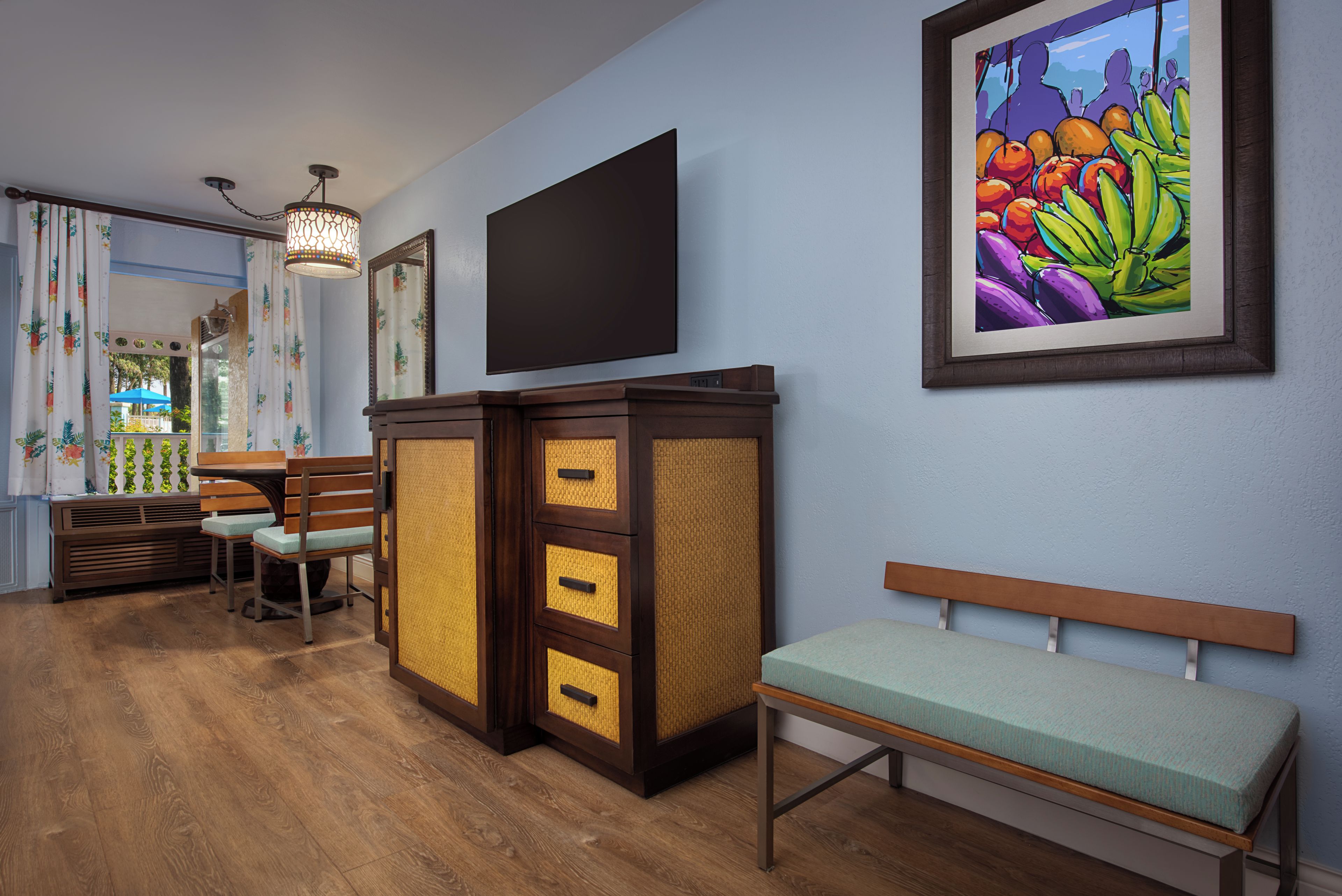A room with a wooden bench, a television mounted on the wall, and a colorful painting.