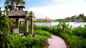 A pathway leading to a gazebo with a view of a body of water and a distant building. - Disney's Caribbean Beach Resort (Lake Buena Vista)