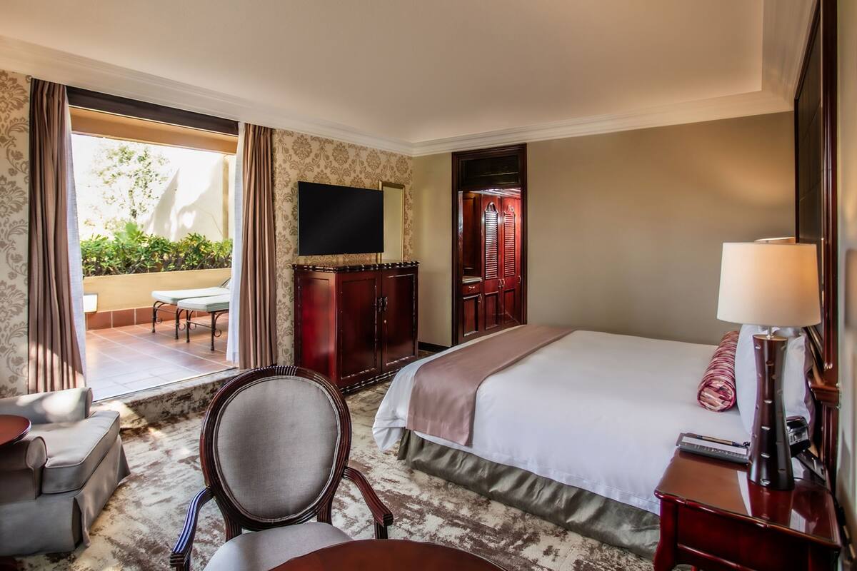 Une chambre d’hôtel avec un grand lit, une télévision, un bureau avec une lampe, une chaise et une vue sur l’extérieur.