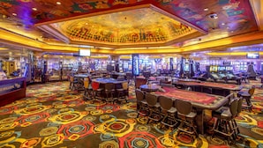 A casino interior with slot machines, blackjack tables, and a colorful carpet. - The Cascades Hotel at Sun City Resort (Moses Kotane)