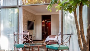 A room with a bed, a TV, and a seating area with chairs and a table. - The Cascades Hotel at Sun City Resort (Moses Kotane)