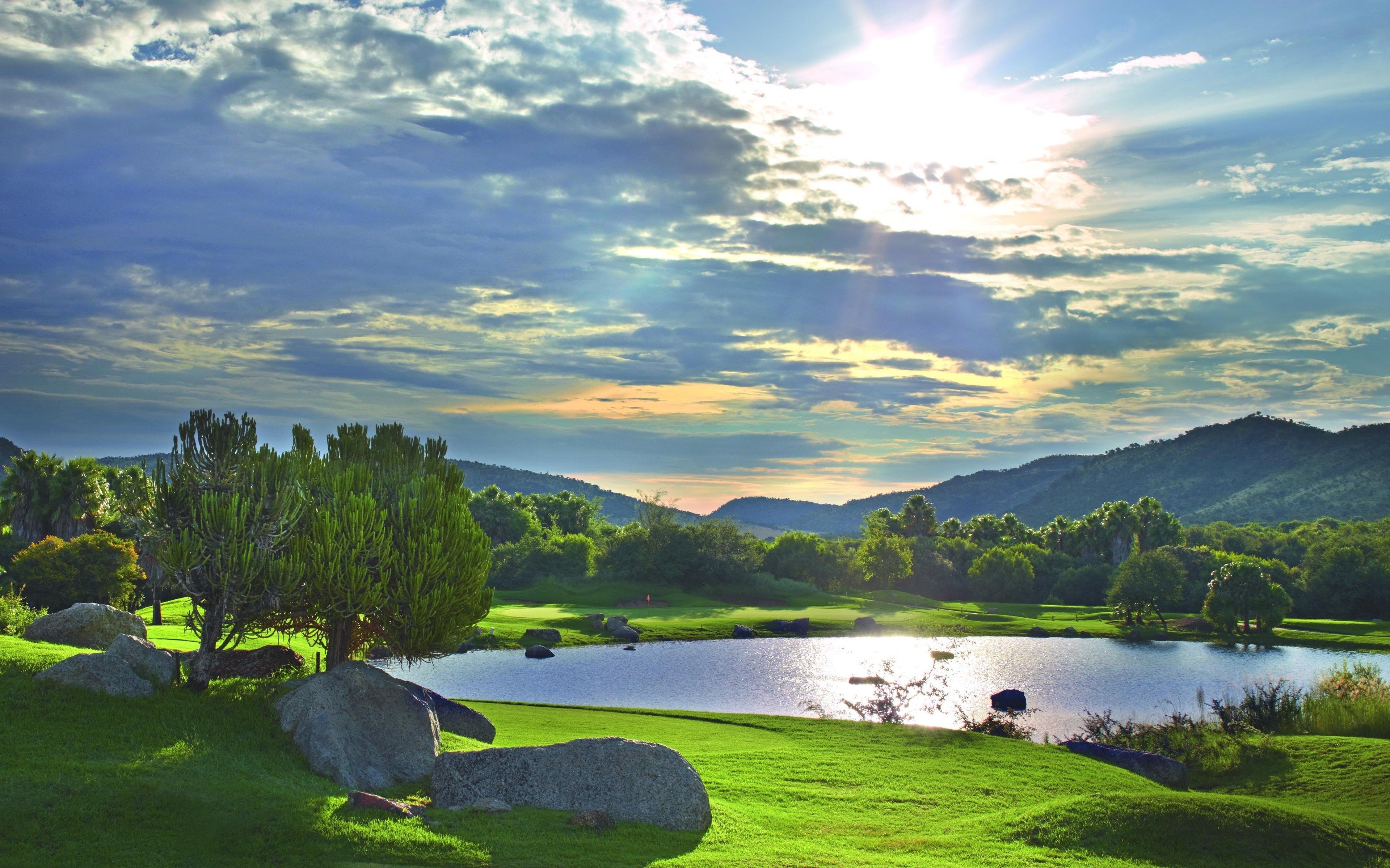 Un parcours de golf avec un lac, de l’herbe verte et des arbres.