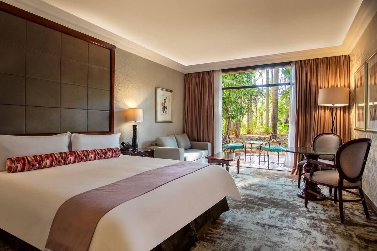 Une chambre d’hôtel avec un grand lit, un canapé, une table à manger et une vue sur l’extérieur.