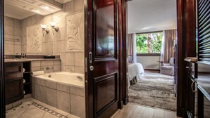 A modern bathroom with a bathtub, vanity, and two wall-mounted lights. - The Cascades Hotel at Sun City Resort (Moses Kotane)
