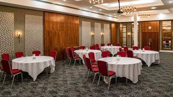 A conference room with round tables, red chairs, and patterned carpet.