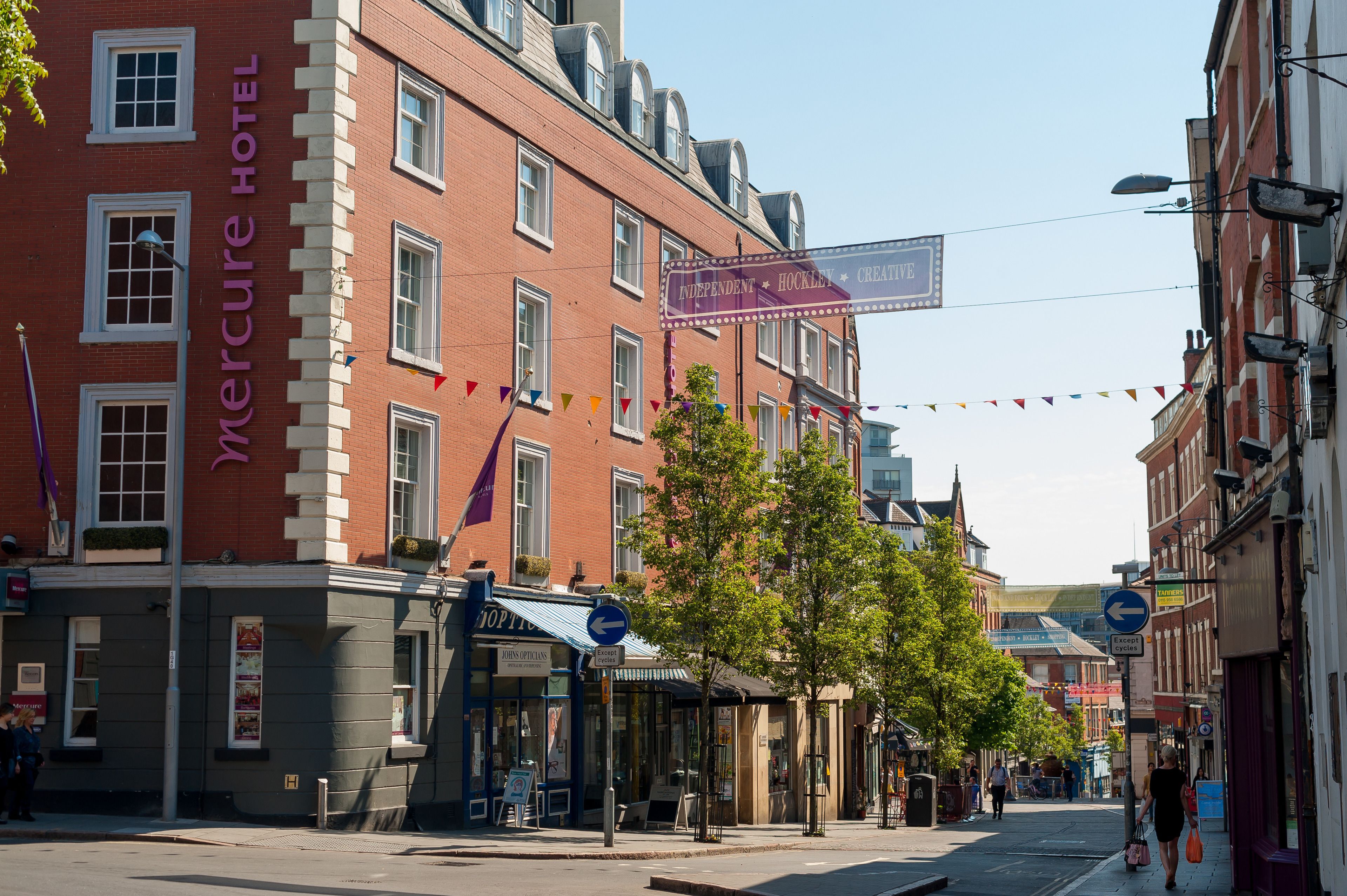 A Mercure Hotel with a classic red brick facade, a signboard advertising 'Independent Hockley Creative', and a blue directional sign on the street.