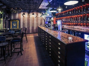 Un espace bar avec un comptoir, des tabourets et un mur rempli de bouteilles d’alcool.