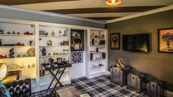 A room with a checkered floor, a television mounted on the wall, and a collection of shelves with various items.