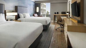 Una habitación de hotel con dos camas, un escritorio, un televisor y vistas a la ciudad.