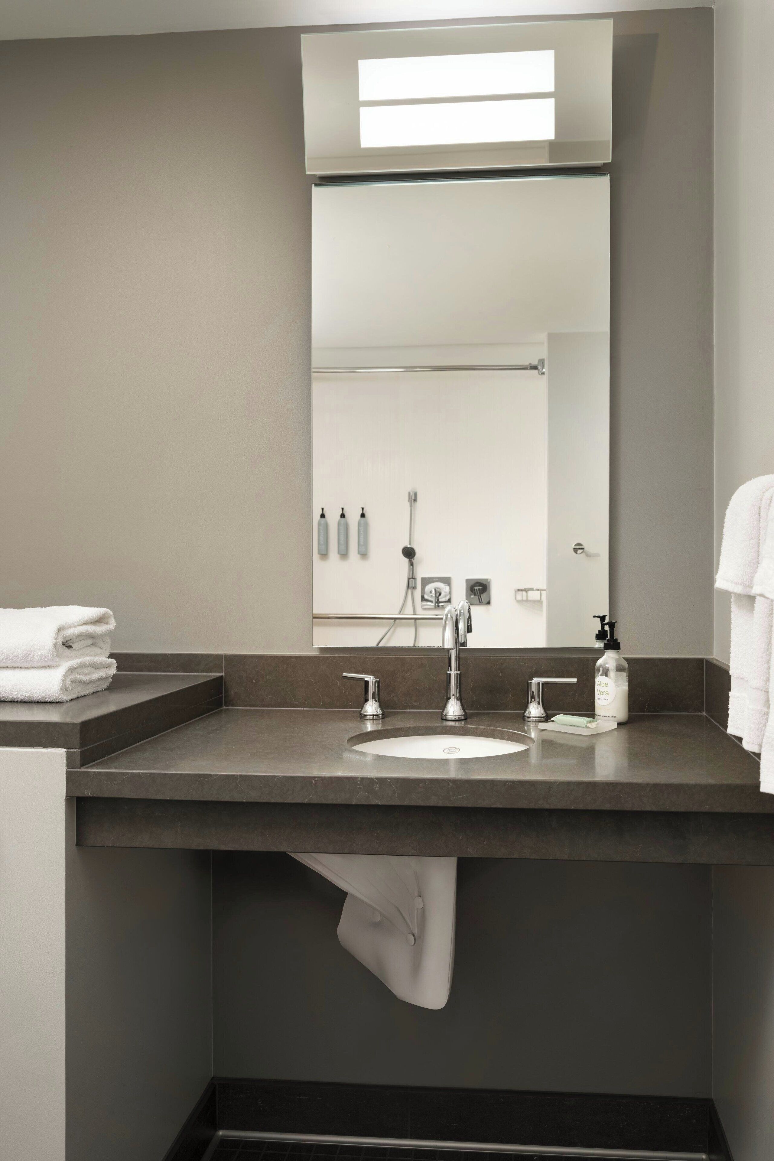 A modern bathroom with a large mirror, a sink, and a towel rack.