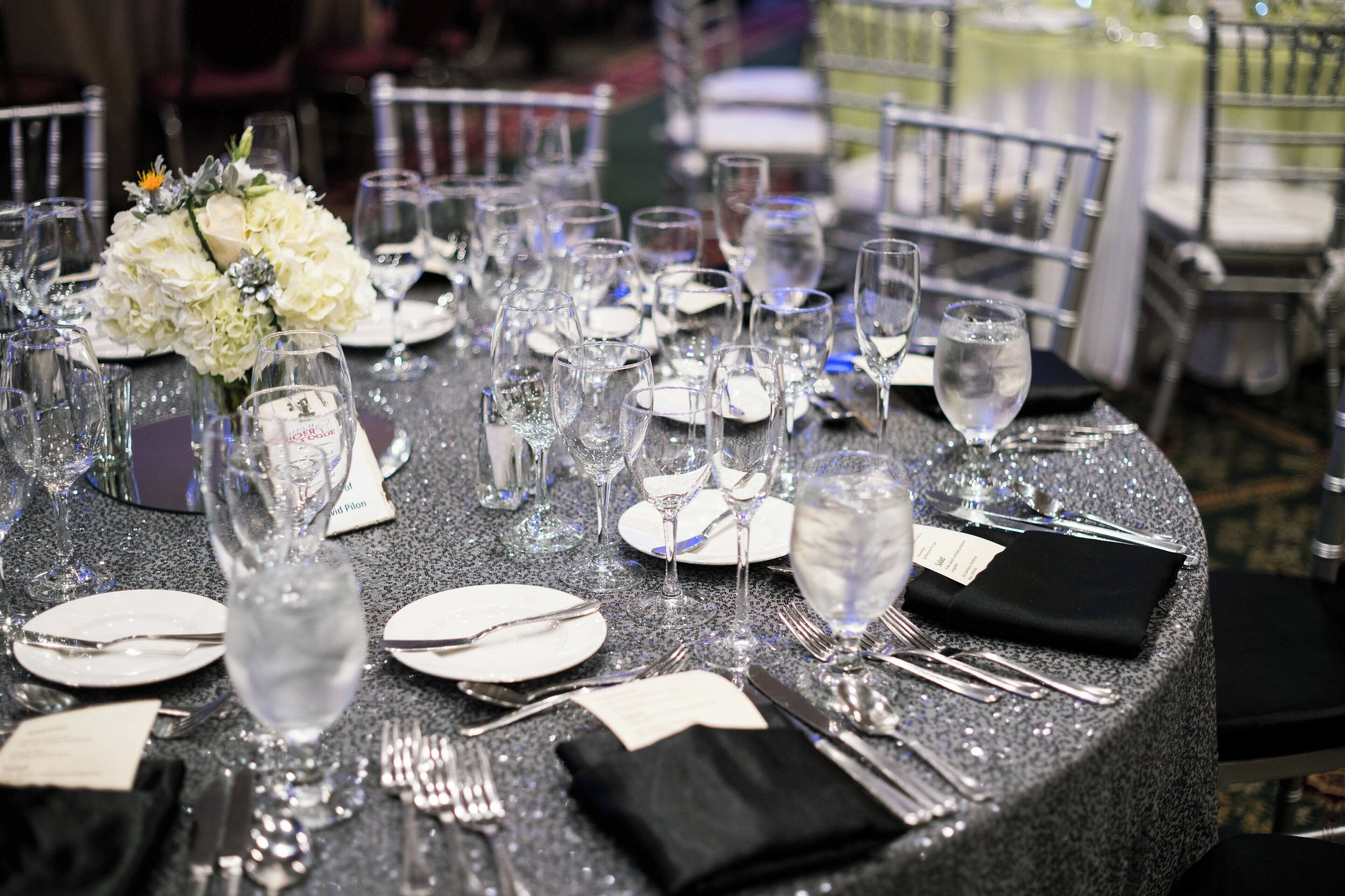 A table set for a formal event with multiple wine glasses, plates, and cutlery.