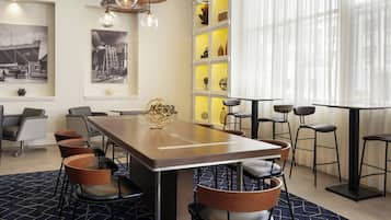 Uma sala de jantar moderna com uma mesa comprida, várias cadeiras e iluminação pendente.